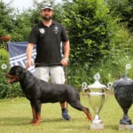 Oliver Neubrand con un Rottweiler y trofeos de competición