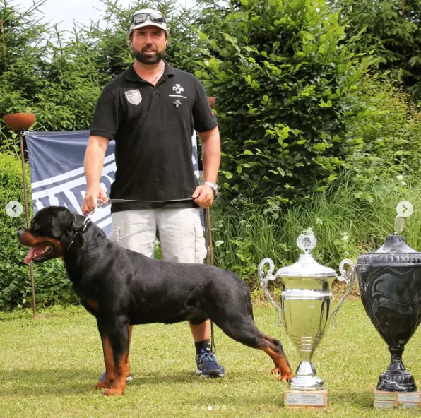 Oliver Neubrand con un Rottweiler y trofeos de competición